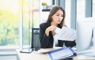 Businesswoman sitting in front of computer and doing some paperwork while working in the office. Businesswoman working on computer in her workplace.