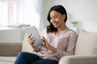 © fizkes - Smiling african American woman busy browsing tablet