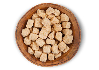 Wall Mural - Wooden bowl plate of natural brown unrefined sugar cubes on white background.