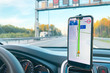 The smartphone in the car is used for navigation or GPS. The movement of the car with a smartphone in the holder. Mobile phone isolated white screen. Copy spaces. Vehicle interior.