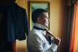 A handsome man ties a tie. The groom is preparing for the ceremony