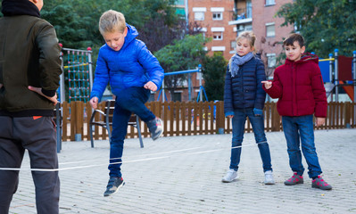 Wall Mural - Kids skipping on chinese jumping elastic rope in yard