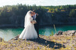 The bride and groom kiss on the background of the lake. Couple of lovers on the background of water. Classic wedding photography
