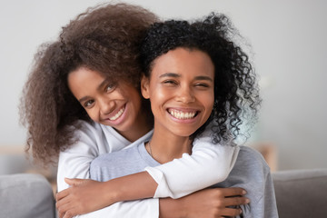 Happy african family mother and teen girl embracing mom, portrait