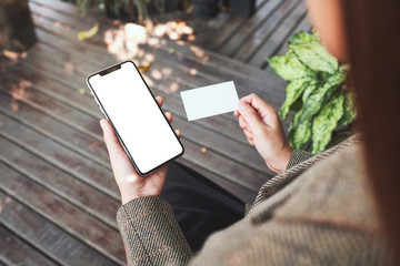 Mockup image of a woman holding white mobile phone with blank desktop screen and a white empty business card