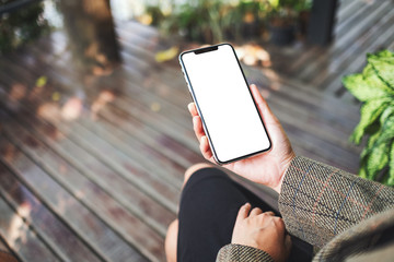 mockup image of a woman holding a black mobile phone with blank white desktop screen