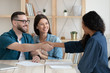 © fizkes - Smiling married couple shaking hands with african american financial advisor.