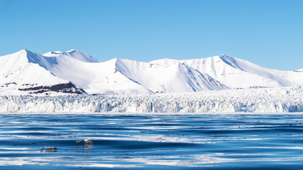 Wall Mural - panoramic view of a glacier and pristine snow covered mountains in nordfjorden, svalbard