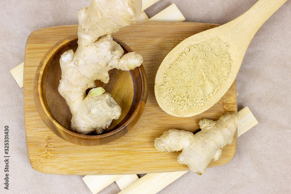 Fresh raw yellow ginger root with ground dry powder in wooden spoon and on wood background. - obrazy, fototapety, plakaty 