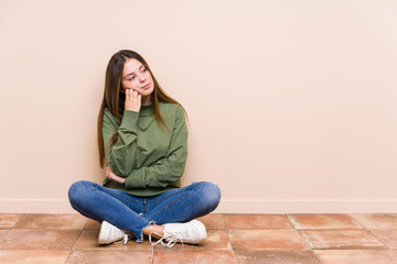 Wall Mural - Young caucasian woman sitting on the floor isolated who feels sad and pensive, looking at copy space.