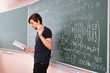 © Mihail - young student in university standing next to the blackboard and thinking at the maths equation