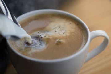 Milk pouring into a coffee mug