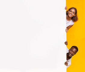 Wall Mural - Afro boy and girl looking from behind advertising board