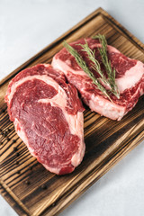 Wall Mural - Raw meat beef steak, with ingredients for cooking on a wooden board and white background. Top view