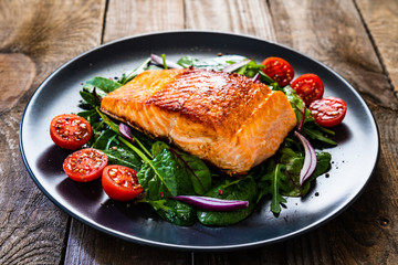 fried salmon steak with vegetables on wooden table