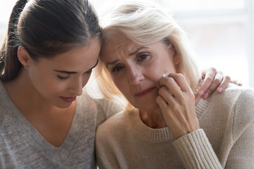 Wall Mural - Close up young grown up worried daughter hugging frustrated mother.