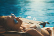 © M-Production - Pretty lady in sunglasses sunbathes near the pool in the summer.