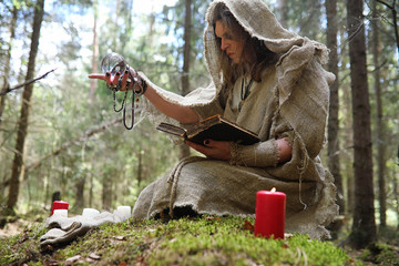 Wall Mural - A man in a cassock spends a ritual in a dark forest