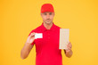 © be free - Get free discount card. Delivered to your destination. Service delivery. Courier and delivery. Postman delivery worker. Handsome man red cap yellow background. Delivering purchase. Business contact