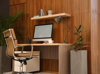 Poster - Comfortable workplace with computer near wooden wall in stylish room interior. Home office design