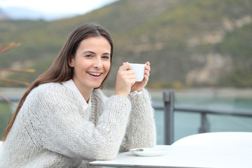 Wall Mural - Happy girl holding coffee mug looks at camera