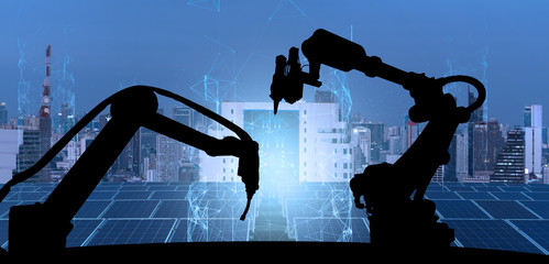 Leinwandbilder - Silhouette of modern automation robot arms with Ai assistant technology network concept and renewable power city building background.
