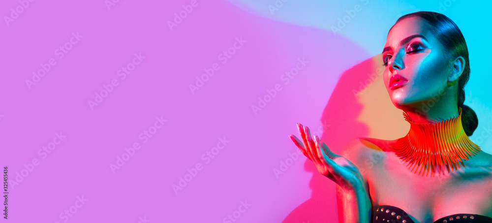 High Fashion model woman portrait in colourful bright neon lights, beautiful party girl with trendy make-up, manicure, hairstyle. Pointing hand, advertising gesture over colorful vivid background - obrazy, fototapety, plakaty 
