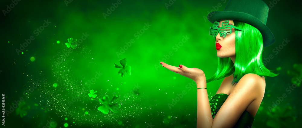 St. Patrick's Day leprechaun model girl pointing hand, holding product on green magic background, blowing flying shamrock leaves. Patrick Day pub party, celebrating. Border art design, Widescreen - obrazy, fototapety, plakaty 