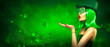 © Subbotina Anna - St. Patrick's Day leprechaun model girl pointing hand, holding product on green magic background, blowing flying shamrock leaves. Patrick Day pub party, celebrating. Border art design, Widescreen