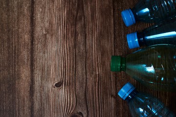 Overhead closeup shot of blue and green plastic bottles on a wooden background