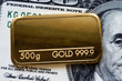 © vladk213 - Gold bar weighing 500 grams 999.9, fineness against a blurred background of dollar bills.