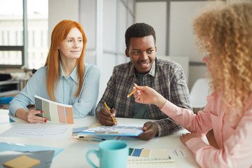 Wall Mural - Portrait of young African-American man discussing creative project during meeting with team in modern office, copy space
