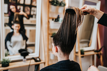 Wall Mural - Beautiful young woman preparing for haircut at a beauty salon.