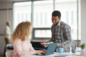 Wall Mural - portrait of young african-american man discussing business project with female colleague in modern o