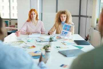 Wall Mural - Portrait of two businesswomen sitting opposite two men while discussing work project, copy space