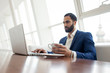 © Богдан Маліцький - young successful businessman use a laptop and drink coffee in the morning at cafe, a freelancer is sitting with a computer in a office