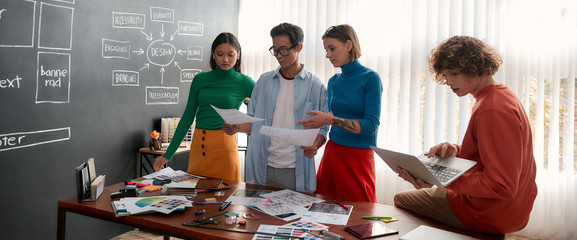 Wall Mural - web site development. creative group of young designers discussing new project while having a meetin