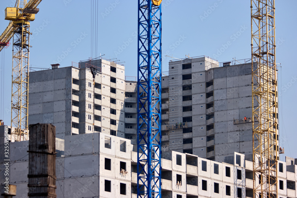 Unfinished cement building at a construction site. Three cranes. New ...