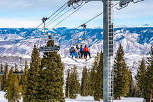 Skiers And Snowboarders Ascend The Alpine Springs Chairlift At The Aspen Snowmass Ski Resort, In The Rocky Mountains Of Colorado On A Partly Cloudy Winter Day. 