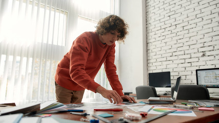 Wall Mural - working on a new project. focused young designer in casual looking at some color swatches while stan