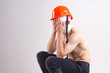 Picture of sufferer male with bandaged head sits on a chair with orange helmet and thinks