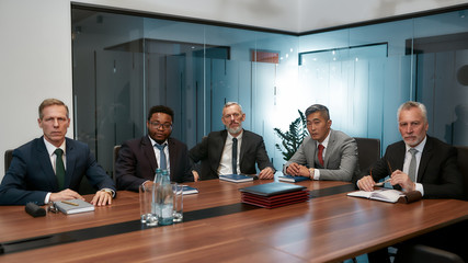 Confident multicultural team. Group of five business people in formal wear looking at camera while sitting together at the office table