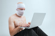 Picture of sufferer male with bandaged head communicates in a laptop