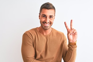 Canvas Print - Young handsome elegant man wearing winter sweater over isolated background smiling with happy face winking at the camera doing victory sign. Number two.