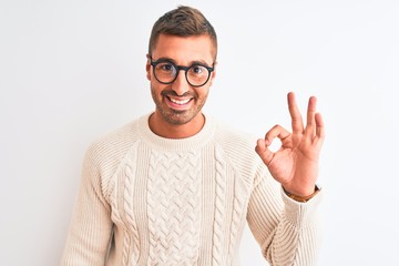 Wall Mural - Young handsome man wearing glasses and winter sweater over isolated background doing ok sign with fingers, excellent symbol