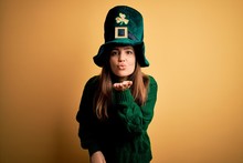 Young Beautiful Brunette Woman Wearing Green Hat On St Patricks Day Celebration Looking At The Camera Blowing A Kiss With Hand On Air Being Lovely And Sexy. Love Expression.