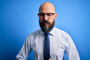 Sticker - Handsome business bald man with beard wearing elegant tie and glasses over blue background with hand on stomach because indigestion, painful illness feeling unwell. Ache concept.