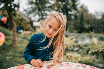 Portrait of young lovely girl lies on the coverlet in the garden and smile