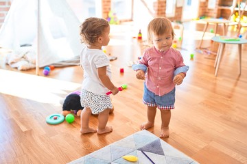 Adorable toddlers playing around lots of toys at kindergarten