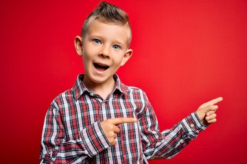 Young little caucasian kid with blue eyes standing wearing elegant shirt over red background smiling and looking at the camera pointing with two hands and fingers to the side.